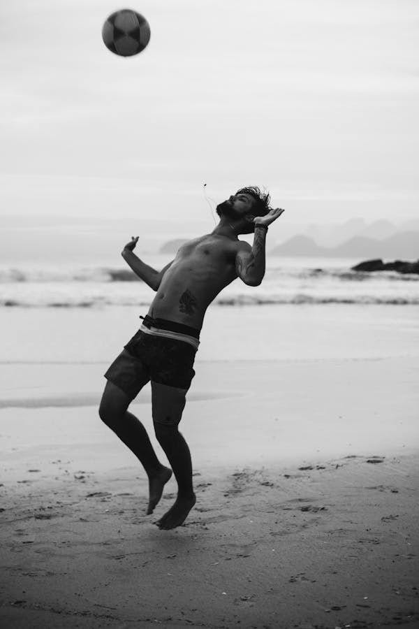 A man playing in football in sea beach 